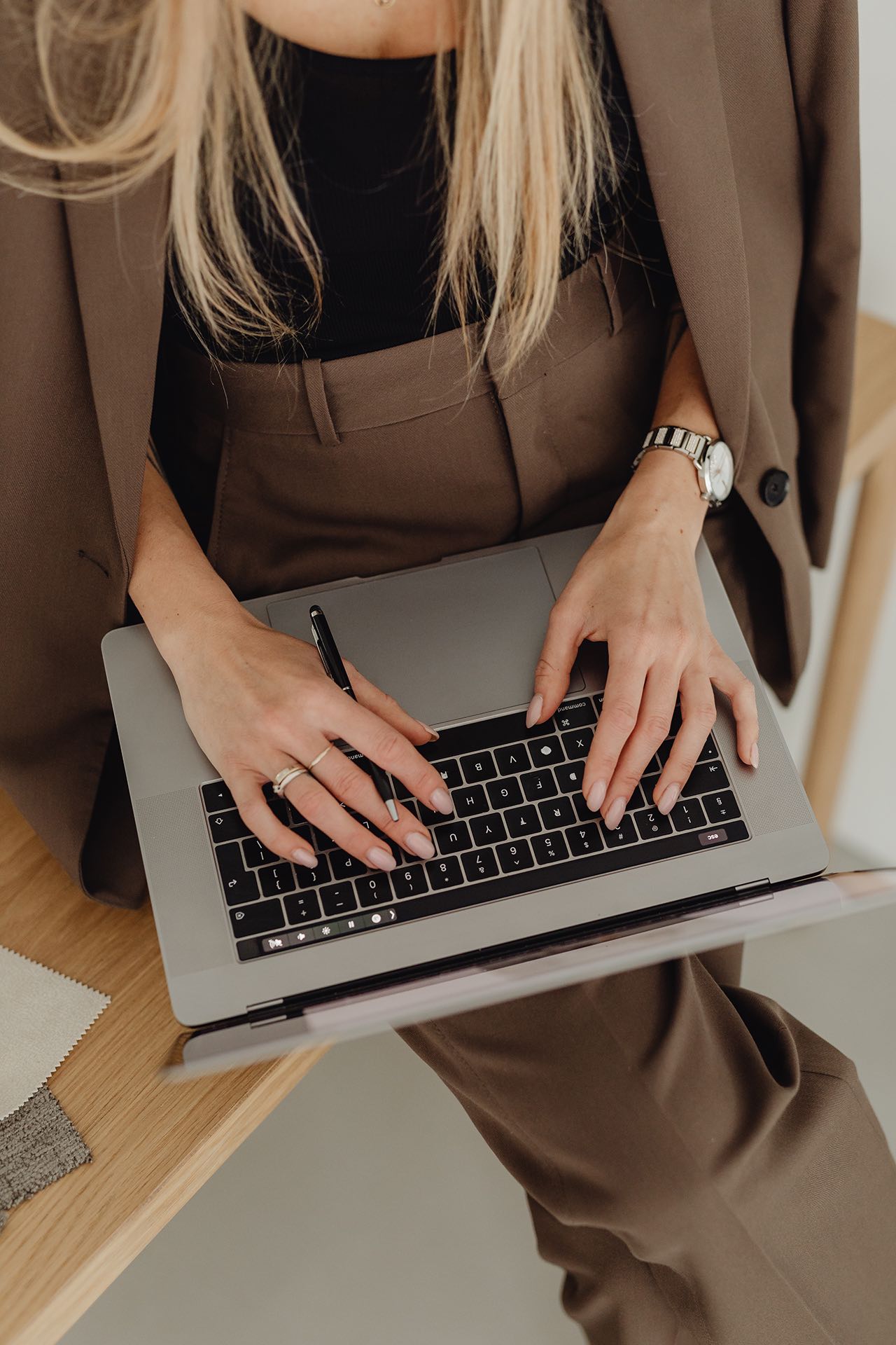 female business owner dressed in a brown suit typing on a laptop to research marketing ideas