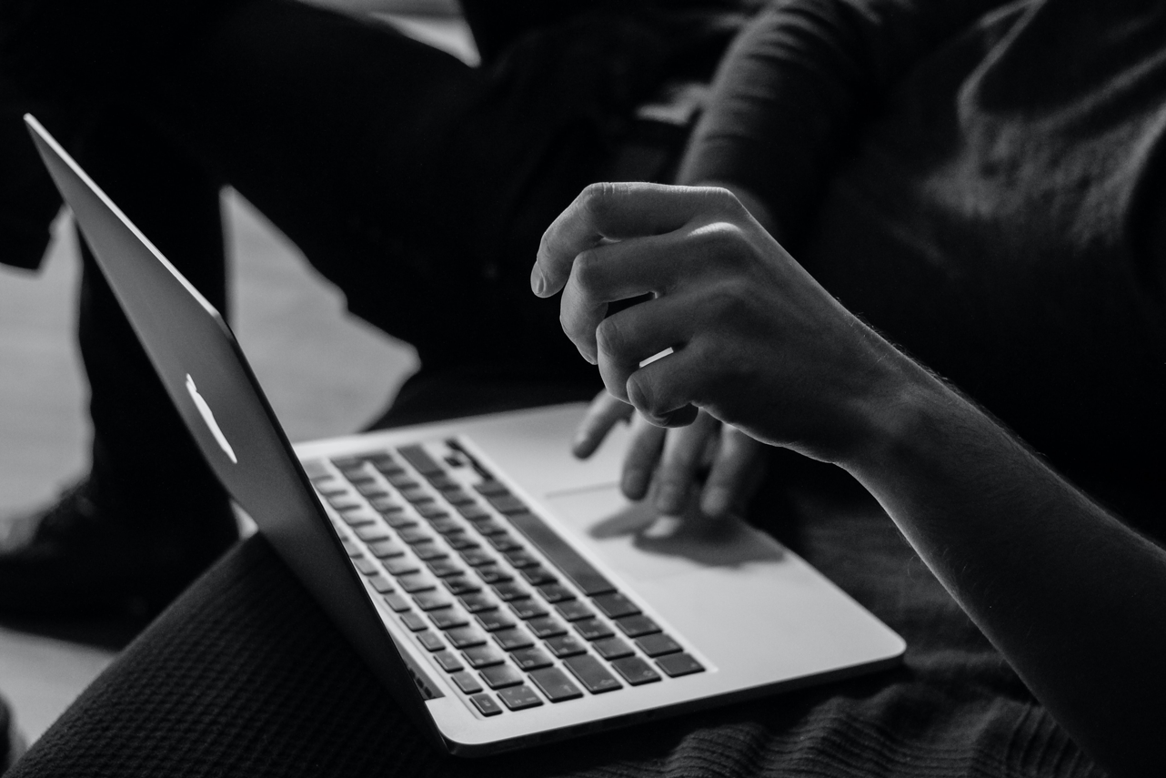 side angle of hands touching a laptop touchpad in black and white